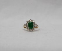 An emerald and diamond ring set with a central oval emerald,