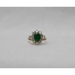 An emerald and diamond ring set with a central oval emerald,