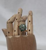 An emerald and diamond cluster ring set with a central emerald,