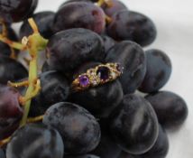 An Amethyst and diamond ring set with three graduated amethysts and four old cut diamonds to a 9ct