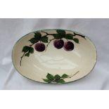 A Llanelly pottery oval bowl decorated with plums and leaves to a green line rim,