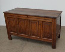 An 18th century oak coffer, the planked rectangular top above a four-panelled front on stiles,