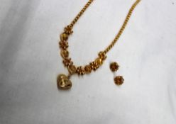 A yellow metal necklace with a central heart, diamond and star shaped links, with matching earrings,