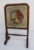 A Victorian walnut framed fire screen, with a domed top on four scrolling feet,