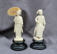 A pair of Indian ivory figures, the lady holding a parasol over her head,