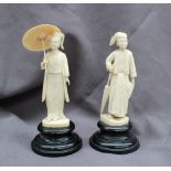 A pair of Indian ivory figures, the lady holding a parasol over her head,