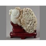 A 19TH CENTURY CHINESE WHITE JADE CARVING, of a sleeping boy on a bee hive the boy in pure white