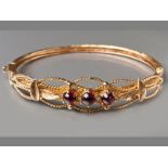 AN 18CT YELLOW GOLD AND CABOCHON GARNET BANGLE, three horizontal claw-set cabohon garnet set in rope