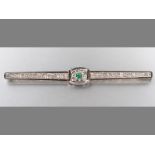 AN 18CT WHITE GOLD AND EMERALD BAR BROOCH, elongated centre claw-set with emerald surrounded by