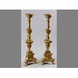A DECORATIVE PAIR OF BRASS PRICKET ALTAR CANDLESTICKS, in the rococco-style, standing on three paw