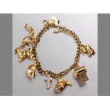 A 9CT YELLOW GOLD CHARM BRACELET, comprising of five various charms, curb-links with heart lock