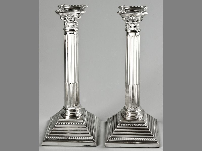 A PAIR OF EPNS CORINTHIAN COLUMN CANDLESTICKS, removable wax pans, terminating on stepped square