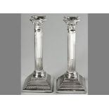 A PAIR OF EPNS CORINTHIAN COLUMN CANDLESTICKS, removable wax pans, terminating on stepped square