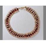 A 9CT YELLOW GOLD AND GARNET BRACELET, comprising forty-four oval garnets, tube-set in chain form