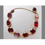 A 9CT YELLOW GOLD AND GARNET BRACELET, eight tube-set garnets ending in a tongue clasp with a claw-