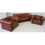 AN ENGLISH CHESTERFIELD SUITE, comprising a couch and two armchairs in red Antique leather, the deep