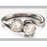 A PLATINUM AND DIAMOND RING, two round brilliant cut diamonds in claw settings, scroll shoulders,