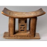 AN ANTIQUE AFRICAN STOOL, the dished seat above elliptical pillars and chip-carved fretted central