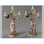 A PAIR OF THREE BRANCH CONTINENTAL CERAMIC FIGURAL CANDELABRA, the arms profusely decorated with