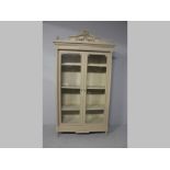 AN EARLY 20TH CENTURY FRENCH STYLE DISPLAY CUPBOARD, the arched pediment with carved ribbons and