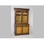 AN EDWARDIAN HARDWOOD DISPLAY BOOKCASE, the moulded pediment above two rectangular glazed doors