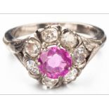 AN 18ct WHITE GOLD, RUBY AND DIAMOND RING, centre ruby in claw setting surrounded by seven rose-