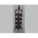 AN EDWARDIAN MAHOGANY PLATE RACK, the four rimmed circular shelves supported on three carved columns