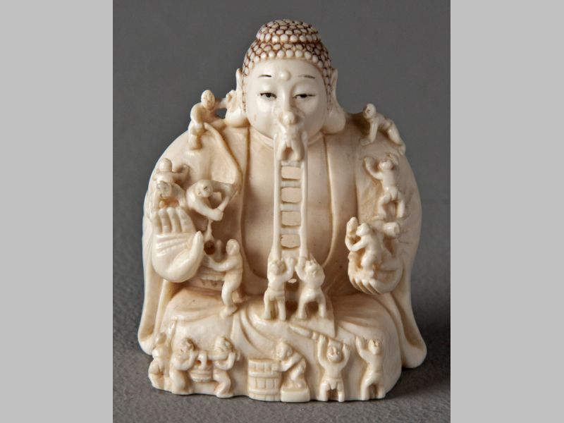 AN EARLY 20TH CENTURY JAPANESE CARVED IVORY NETSUKE, of workmen carving a large Buddha figure, 5cm