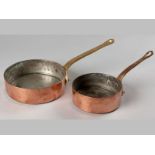 A GRADUATED PAIR OF COPPER AND BRASS SAUCE PANS, by Leon Jaggi & Sons, Deat St. London, 47cm &