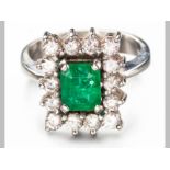 AN 18ct WHITE GOLD, EMERALD AND DIAMOND RING, centre emerald in claw setting surrounded by