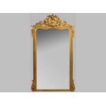 A LARGE GILT FRAMED RECTANGULAR MIRROR, the serpentine top-rail profusely decorated with shell
