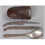 AN INDIAN KNIFE, FORK AND SPOON, in a stamped leather case, the handles decorated with silver and