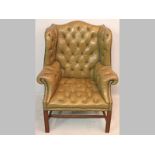 A MAHOGANY AND LEATHER WINGBACK ARMCHAIR, in the Chippendale manner, the deep buttoned green leather