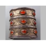 A TURKAMEN TEKKE SILVER AND CARNELIAN SLAVE BANGLE, nine oval carnelians in three segments, 233g.