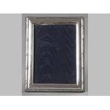 A SILVER PHOTOGRAPH FRAME, LONDON 1997, W.W, the retangular frame embossed with reeds and swags,