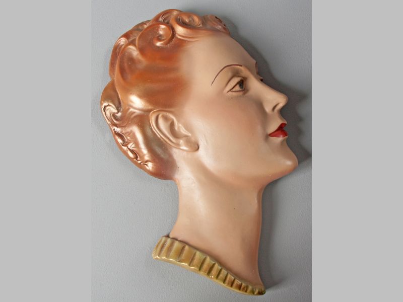 A GOLDSCHEIDER WALL MASK, of a lady with golden brown hair and green collar, 31.5cm high.