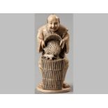 A LATE 19TH CENTURY JAPANESE IVORY CARVING OF A HUMOROUS FARMER, filling a basket with grain,