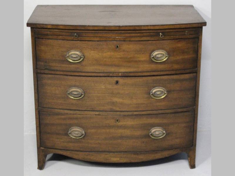 A GEORGIAN MAHOGANY BOW FRONTED CHEST OF DRAWERS, the ebony inlaid top above a brushing slide,