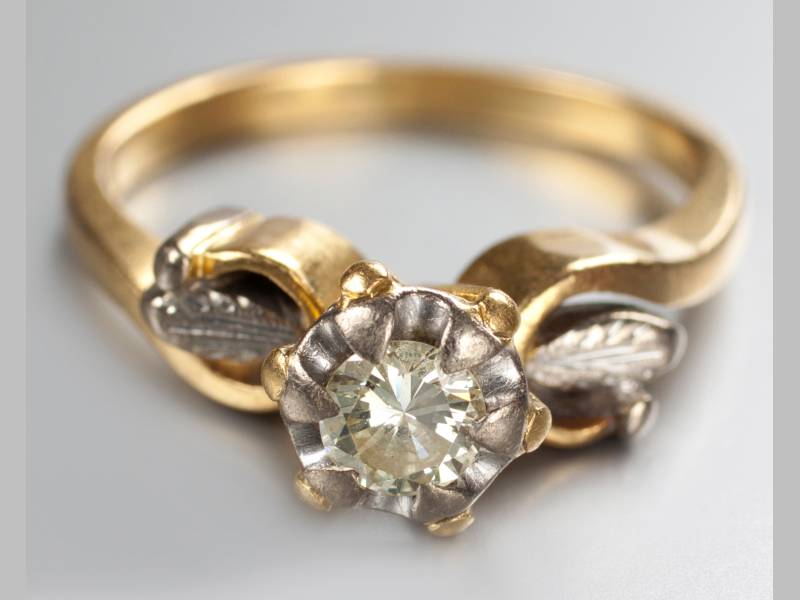 AN 18CT YELLOW GOLD AND DIAMOND RING, brilliant cut claw set diamond, scroll and leaf shoulders,