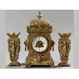 AN EARLY 20TH CENTURY BRASS CLOCK GARNITURE, the square body surmounted with a pagoda and finial,