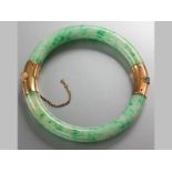 AN 18CT YELLOW GOLD AND MOTTLED JADE BANGLE, hinged, with safety chain, 7.5cm (chain).