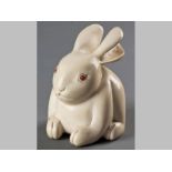 A JAPANESE IVORY CARVING OF RABBIT, EARLY 20TH CENTURY, with red coral eyes, 12cm high. NOT SUITABLE