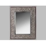 A SILVER FRAMED RECTANGULAR DRESSING TABLE MIRROR, the applied silver border profusely cut-out and