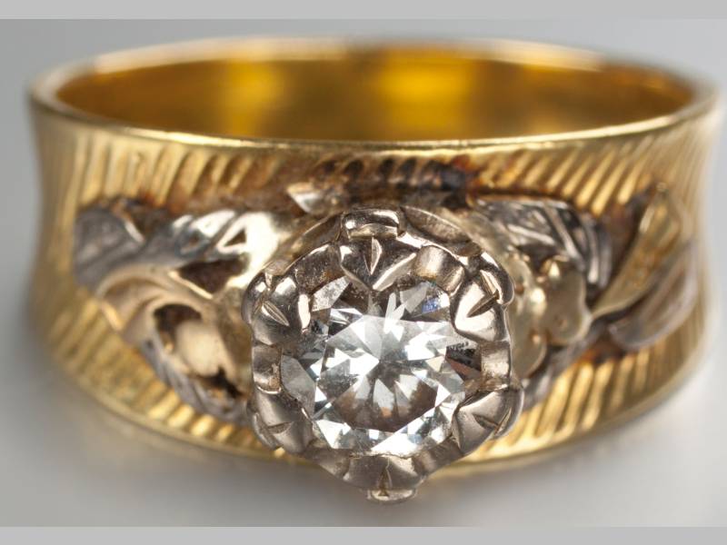 AN 18CT YELLOW GOLD AND DIAMOND RING, diamond claw-set with scroll and leaf shoulders, ending on a