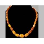 A STRING OF AMBER BUTTERSCOTCH BEADS, graduated with a clasp, 43cm long, 14.2g.