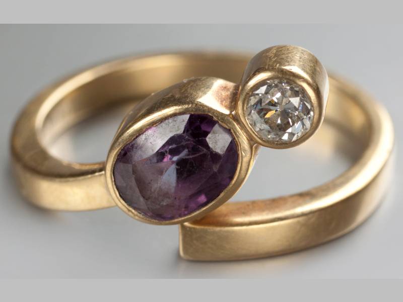 AN 18CT YELLOW GOLD, DIAMOND AND AMETHYST RING, tube set diamond flanked by an oval amethyst, on a