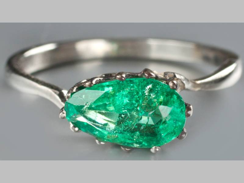 AN 18CT WHITE GOLD AND EMERALD RING, pear shaped emerald claw-set, on a solid band, 2.9g.