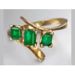 AN 18CT YELLOW GOLD AND EMERALD RING, centre claw set with three emerald-cut emeralds, on split