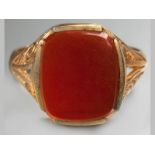 A 9CT YELLOW GOLD AND CARNELIAN SIGNET RING, of square form, on scroll shoulders, ending on a