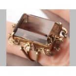 A 9CT YELLOW GOLD AND SMOKEY TOPAZ RING, rectangular topaz claw set on scroll frame with wide